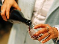 Woman pours red wine into a glass