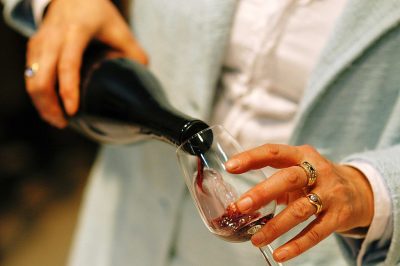 Woman pours red wine into a glass