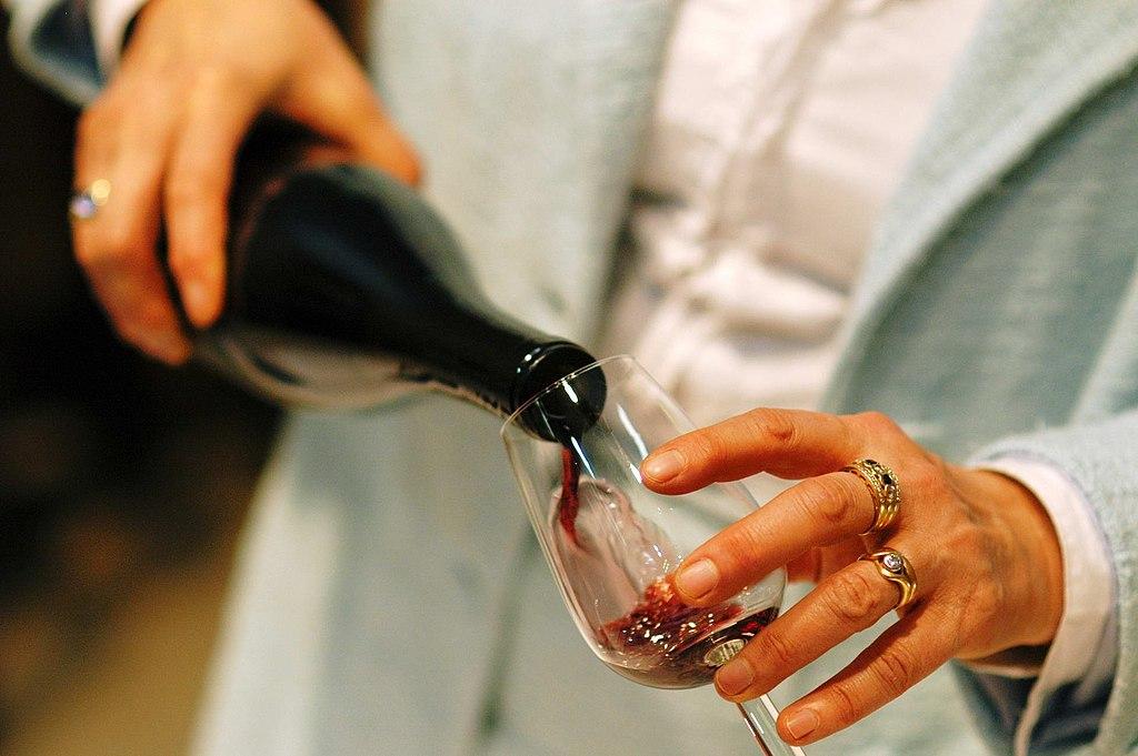 Woman pours red wine into a glass