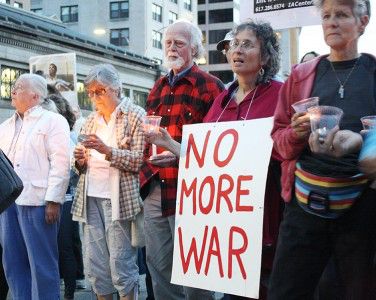 Bostonians hold candles and signs at the Syria vigil Monday night on Park Street near the Boston Common. The vigil began as a peaceful gathering but became heated as the vigil was interrupted by screaming citizens. PHOTO BY MAYA DEVEREAUX/DAILY FREE PRESS STAFF