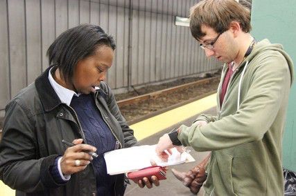 College of Engineering freshman Micheal Gutman collects a signature from Boston registered voter Celeste Scott-Walker for a petition for a higher minimum wage Wednesday afternoon at the Kenmore T stop. PHOTO BY ALEXANDRA WIMLEY/DAILY FREE PRESS CONTRIBUTOR 