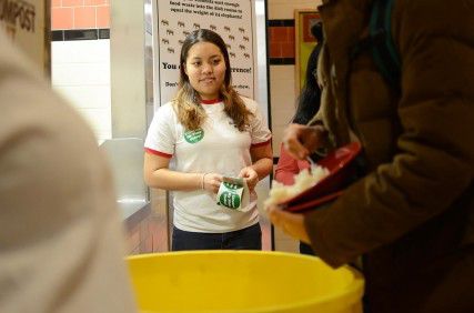 College of General Studies sophomore Sarah Moran hands out stickers saying “I cleaned my plate” to students at the West Campus dining hall Tuesday evening as a part of Club GiiVE’s compost event that emphasizes reducing food waste. PHOTO BY MIKE DESOCIO/DAILY FREE PRESS STAFF