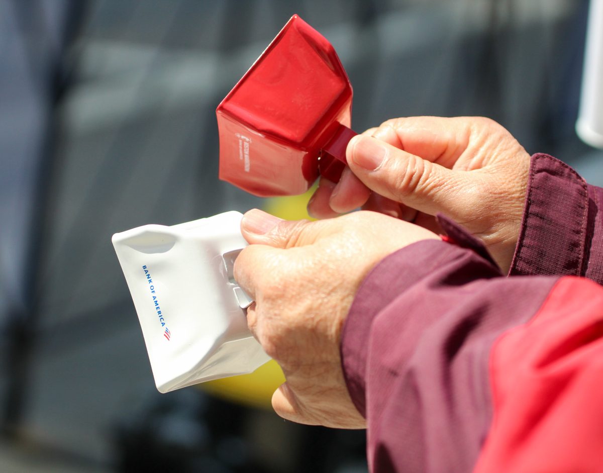A spectator rings bells by the finish line of the marathon. 