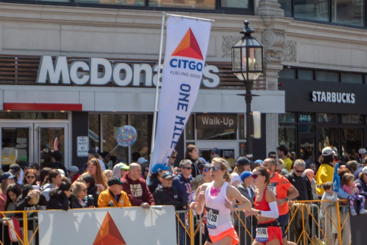 Runners pass by a “one mile to go” sign in Kenmore. 