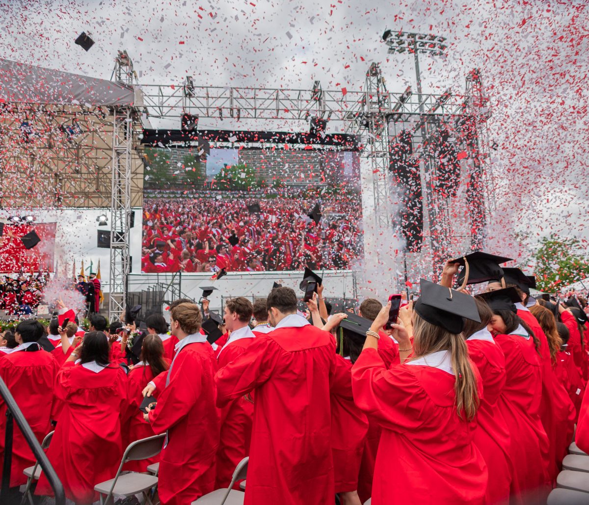 Graduates record videos and throw their caps in the air as confetti falls to signify the end of Commencement.