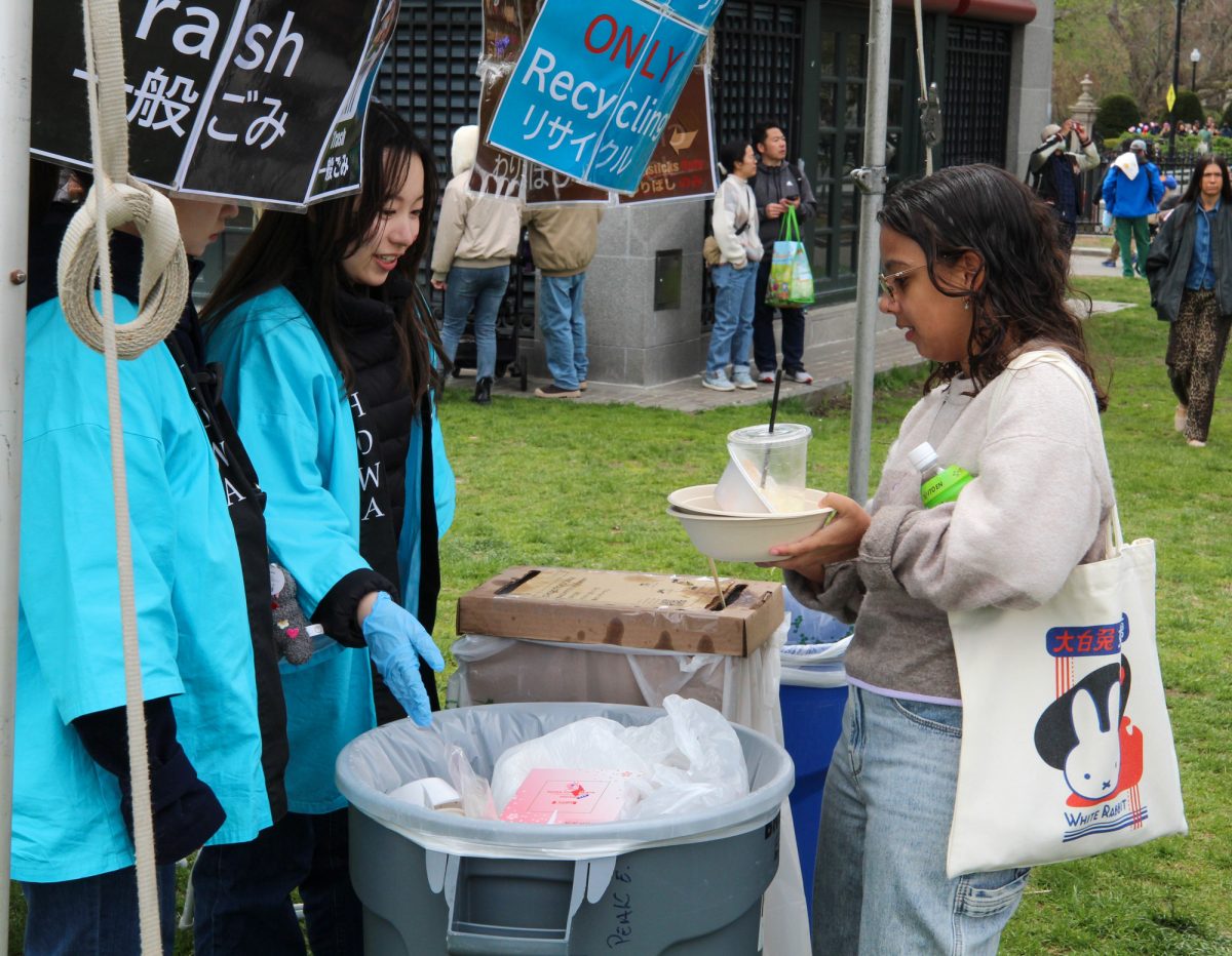 Volunteers guide an attendee at the Trash and Recycle Sustainability station at the festival. 