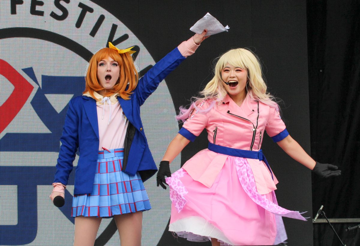 The host and cosplayer react to the applause of the audience during the Cosplay Death Match. 