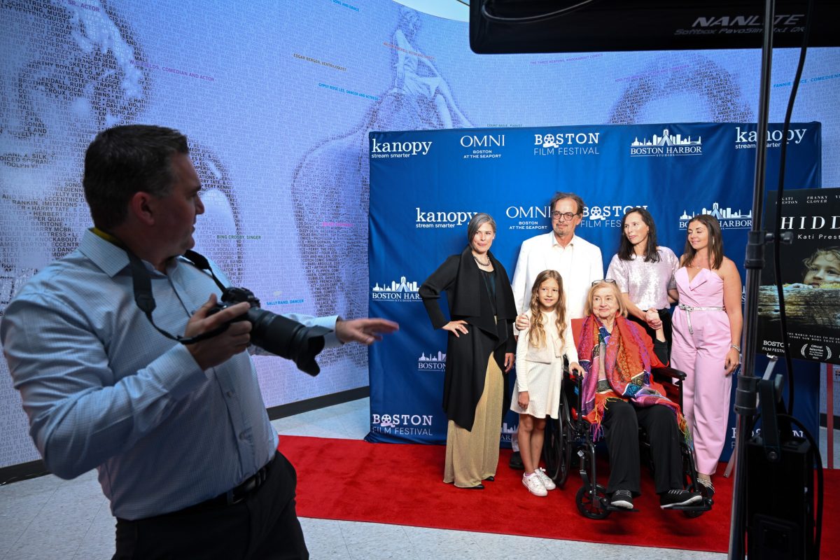 A photographer directs the team members of “Hidden: The Kati Preston Story,” and Kati Preston in the red top. 