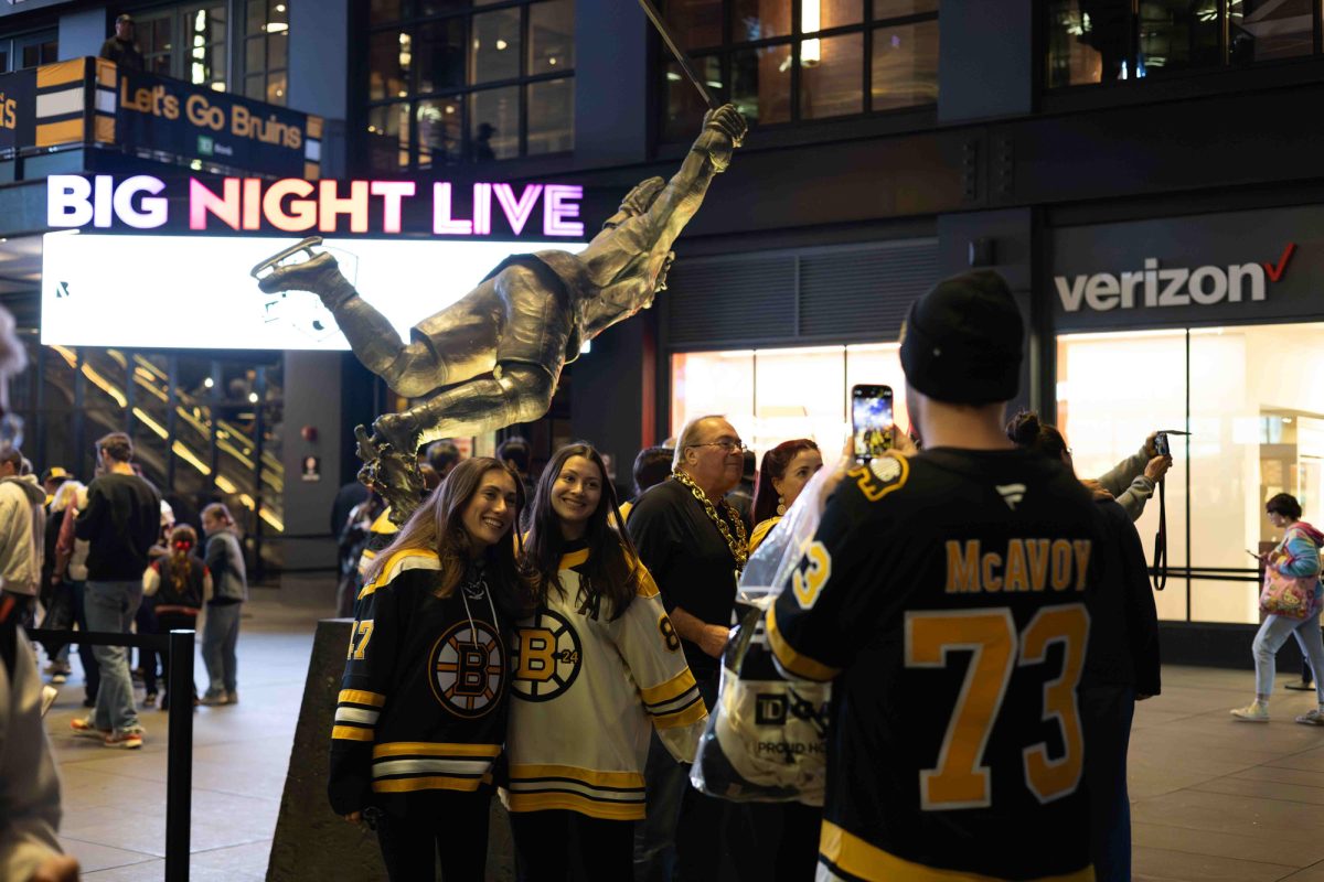 Fans pose for a photo in front of the Bobby Orr statue, a former Bruins defenseman. 
