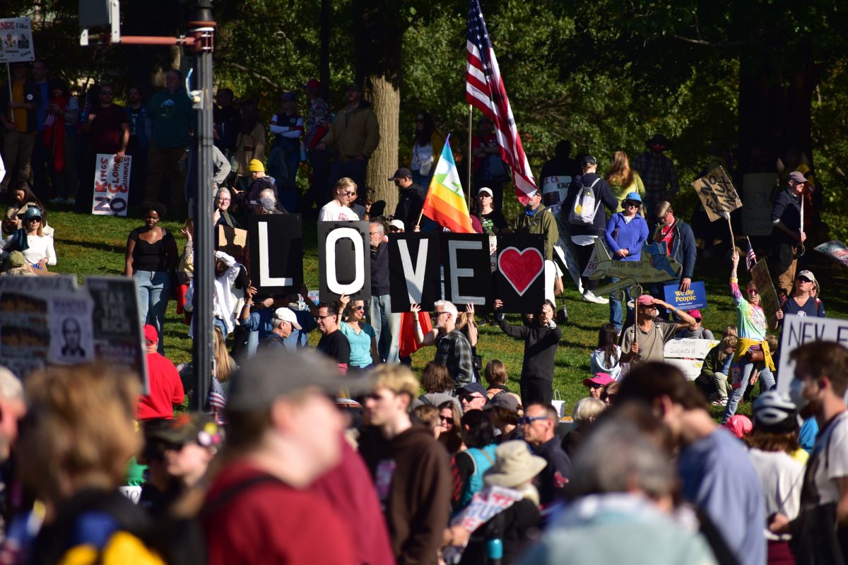 Protesters hold up a pride flag and letters spelling love in support of the queer community. 