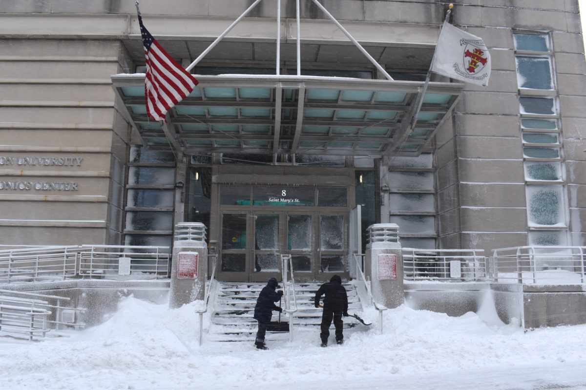 People shovel snow outside the Boston University Photonics Center during Monday’s blizzard. BU cancelled classes Monday and Tuesday, pushing back students’ and professors' academic plans.

