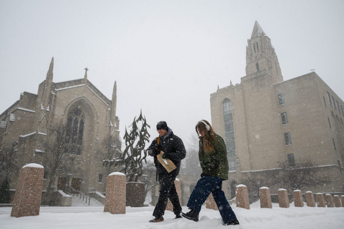 Two pedestrians trudge down Commonwealth Avenue in the winter weather.
