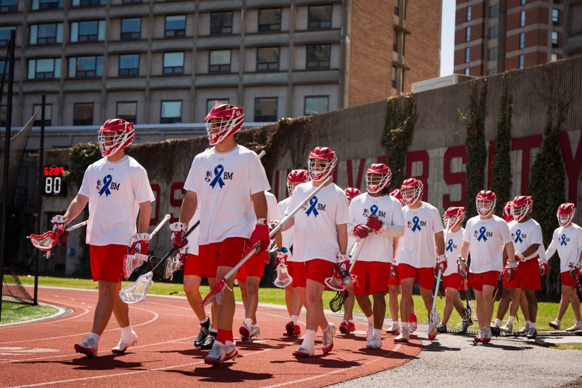 The BU men’s lacrosse team walks out for warmups for their matchup against the Bucknell University Bisons on April 11. The team wore t-shirts honoring Brian Maggiacomo, sophomore defender Zac Maggiacomo’s father, who is facing an ongoing battle with colon cancer during their game facing the Bisons. 