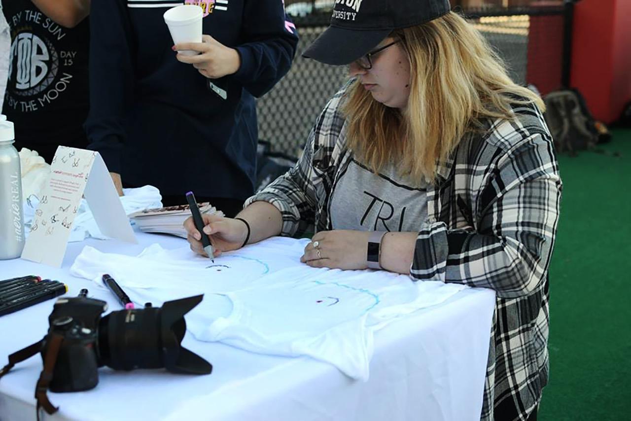 A student draws on a T-shirt at Aerie’s “Shape of You” event on New Balance Field Sunday afternoon. PHOTO COURTESY SAVANNAH MACDONALD