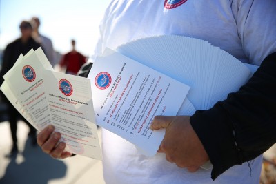 A BU police officer hands out fliers to students on Commonwealth Avenue to garner support for the unionization of BU Police Officers and Sergeants. PHOTO BY SARAH SILBIGER/DAILY FREE PRESS STAFF 