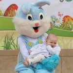 easter bunny mascot holds a baby