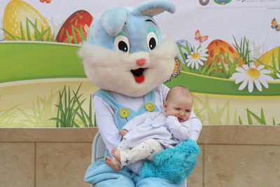easter bunny mascot holds a baby
