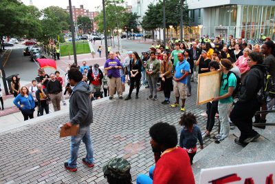 Brock Satter, the main organizer of a protest at the MBTA's Ruggles Station Friday evening, tells the crowd what the group Mass Action Against Police Brutality demands of the police and government. PHOTO BY ABIGAIL FREEMAN/ DAILY FREE PRESS STAFF