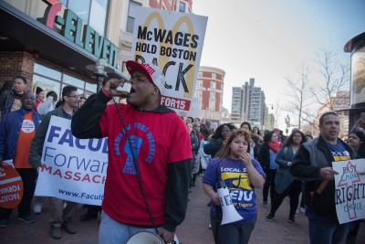 After protesting in front of President Brown's office, Darius Cephas, 25, leads protestors in a chant as they march through Kenmore Square toward the Massachusetts State House. PHOTO BY LEXI PLINE/DAILY FREE PRESS STAFF