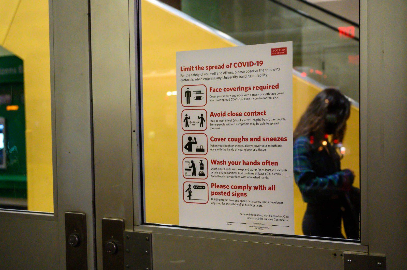 covid-19 protocols sign on the door of warren towers at boston university