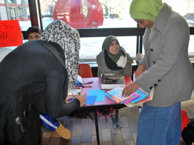 Taiba Zahir (CAS '17) and Maryan Sharif (CAS '17) sign cards Thursday for Boston University facilities workers who worked during winter storm Juno. Annie Khanani (CAS '18) volunteers at the table in the George Sherman Union. PHOTO BY JACQUELYN BUSICK/DAILY FREE PRESS STAFF