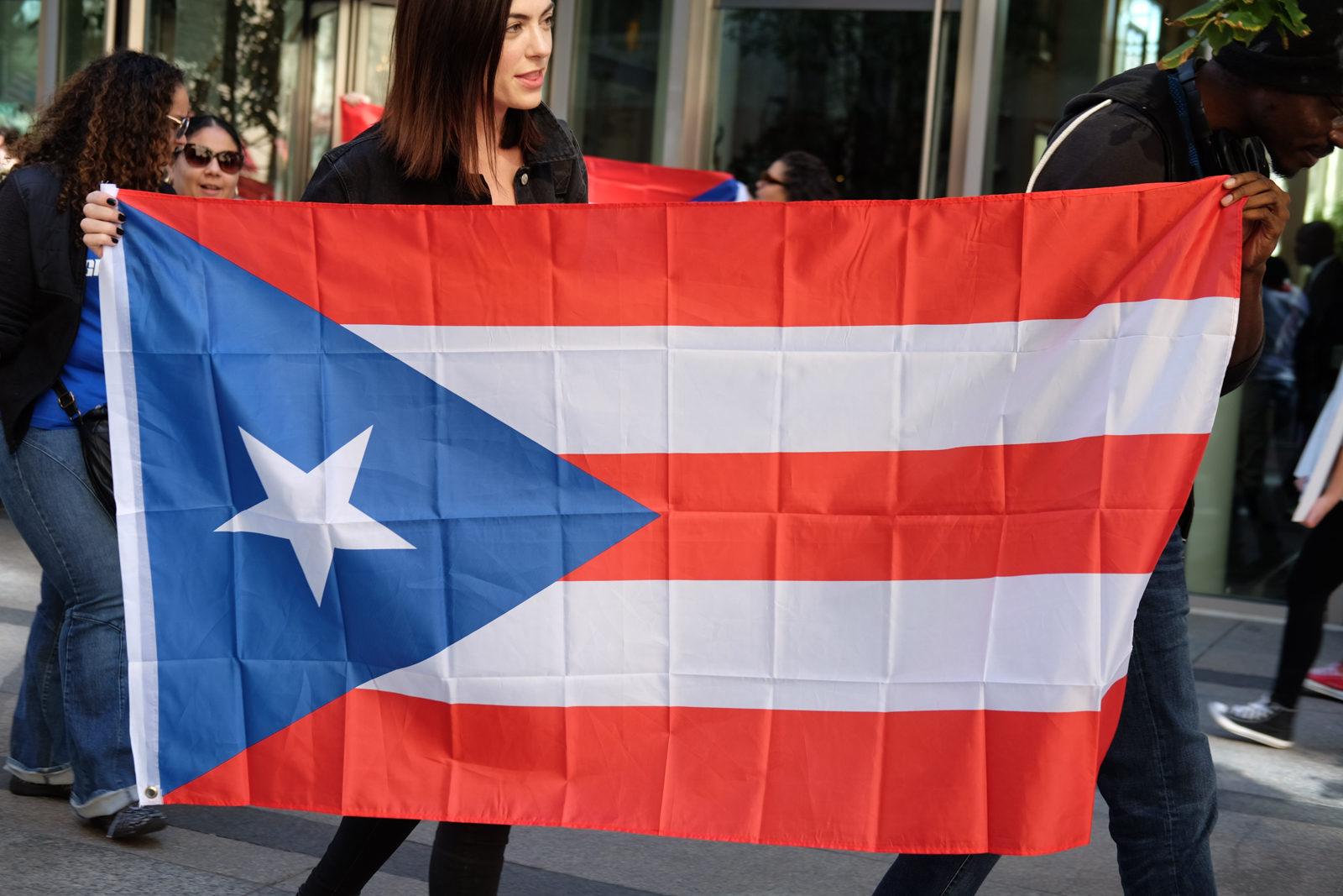 Protesters hold up a Puerto Rican flag on Oct. 21 at a rally against Puerto Rican debt holder the Baupost Group. PHOTO BY ISABELLLA ARTEAGA/ DAILY FREE PRESS STAFF