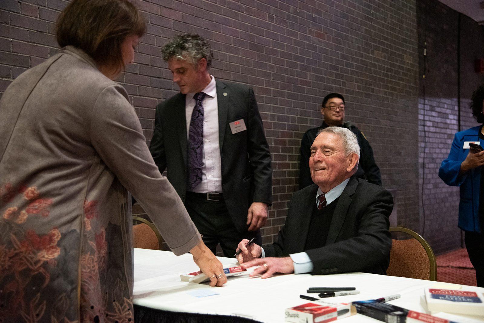 Journalist Dan Rather signs his recent book, “What Unites Us,” after a talk at Boston University’s Metcalf Hall Tuesday. DANIEL MU/ DAILY FREE PRESS STAFF