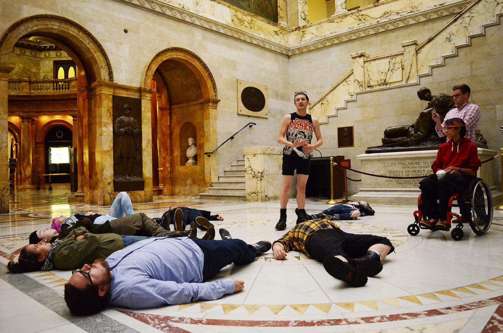 Protesters participate in a die-in for the Statewide Day of Action Opposing Budget Cuts at the State House Tuesday afternoon. PHOTO BY LEXI PEERY/ DAILY FREE PRESS STAFF