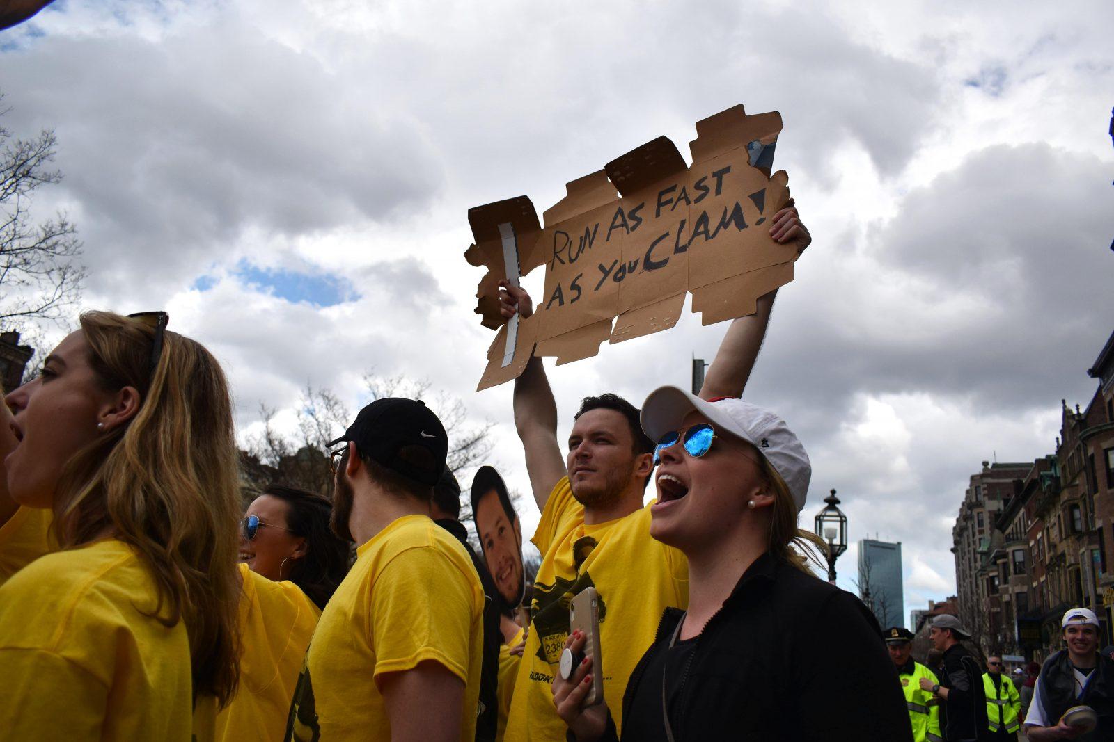 People on the sidelines of the race supporting the marathon runners by holding up homemade signs for encouragement. ALI AUDET/ DFP STAFF
