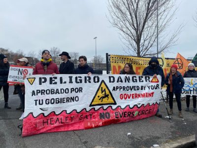 People holding up a sign with a heading that says "Peligro Danger," surrounded by other protestors holding signs