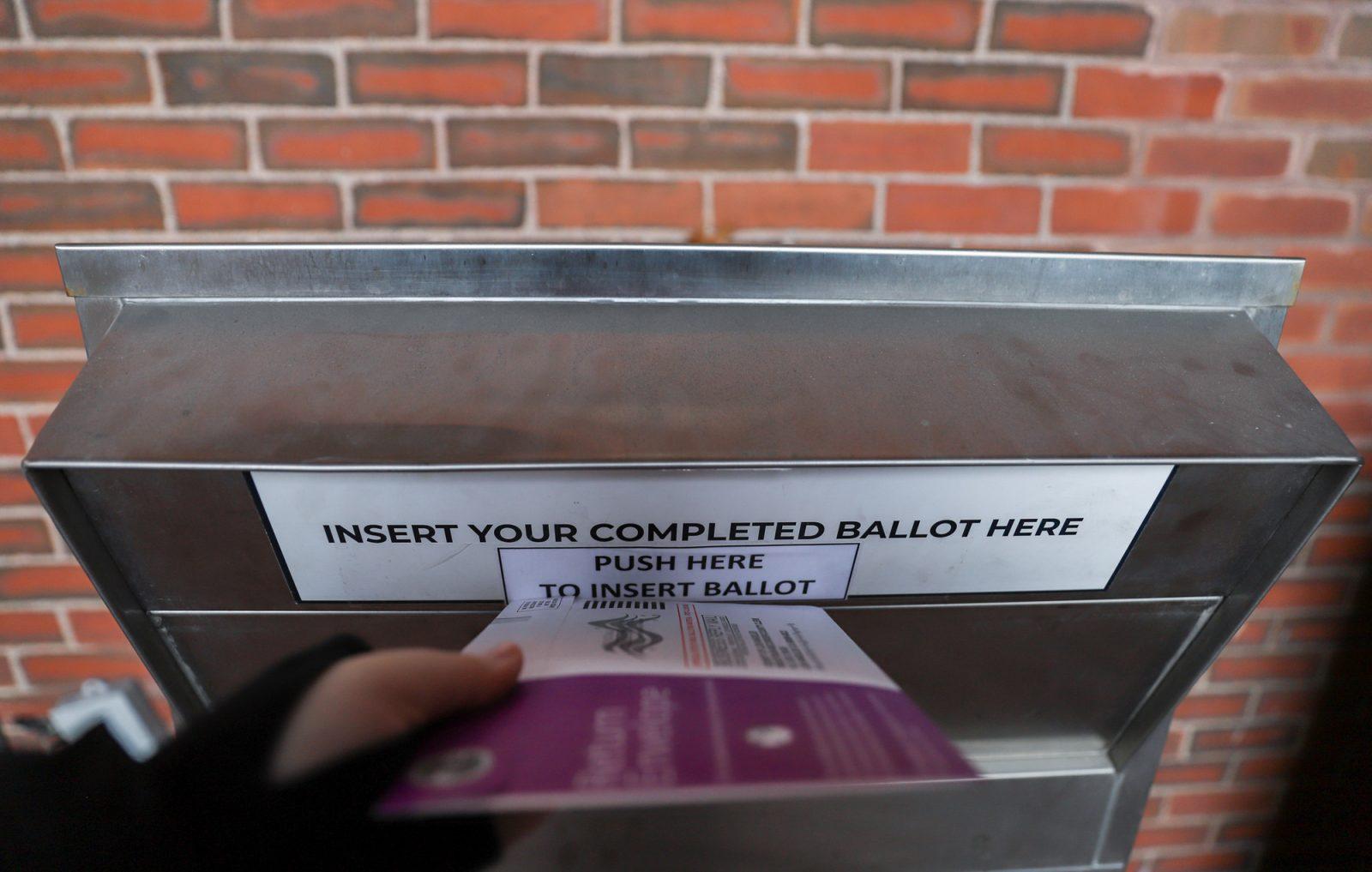 A voter puts an absentee ballot in a ballot drop box by Boston City Hall on Nov. 3. Boston University students who left their absentee ballots at residence hall mailrooms reported delays with their absentee ballots, while others never received them. KATE KOTLYAR/DFP PHOTOGRAPHER 