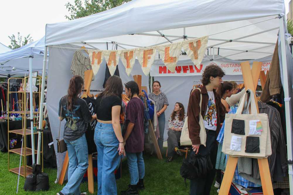 People browsing a stall of vintage clothes at Fenway Flea near Time Out Market. Thrifting and browsing flea markets have emerged as popular pastimes over the last few years in Boston. ISABELLA OLAND/ DFP PHOTOGRAPHER
