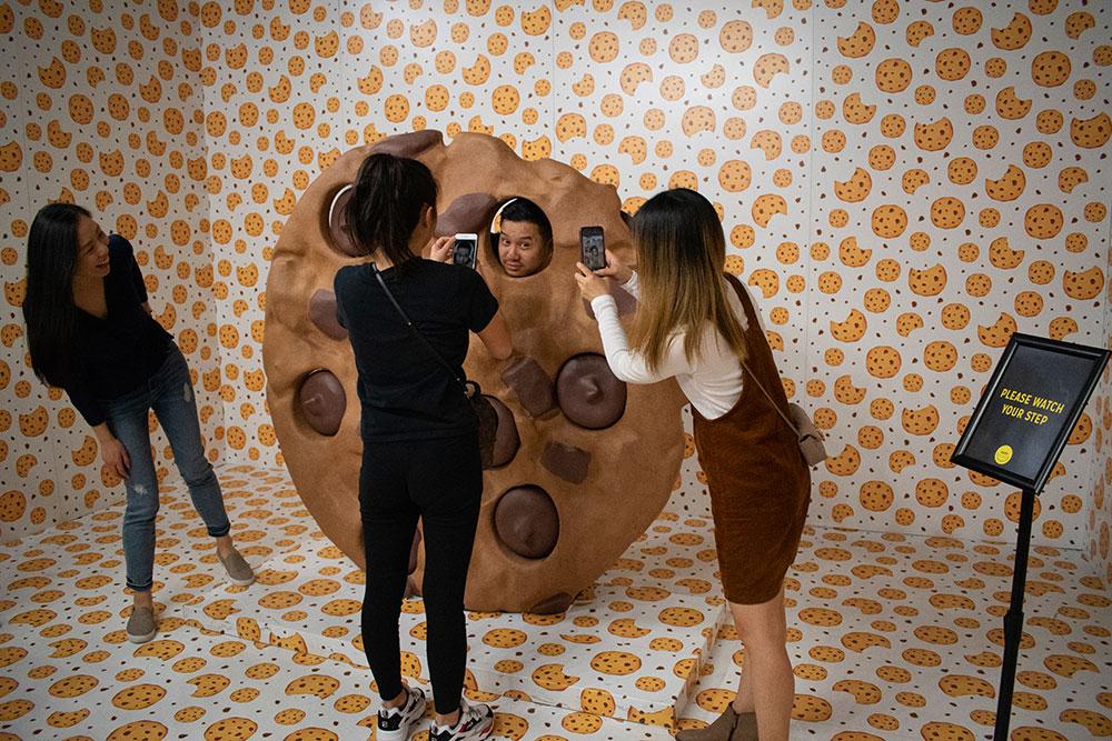 A man visiting the Happy Place pop up pose for a photo inside a giant chocolate chip cookie.
ALI AUDET/ DFP STAFF 
