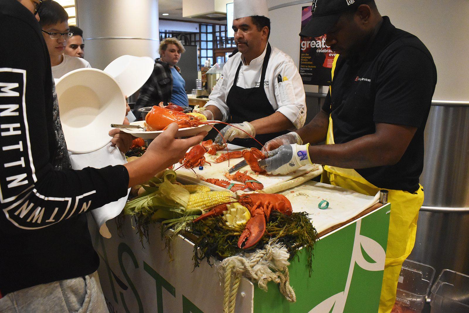 Chefs serve lobster to a line of students at the Warren Towers Dining Hall in 2019. Lobster Night at Boston University is an annual tradition. ALI AUDET/ DFP FILE