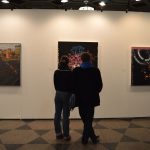 two people look at artwork in a college of fine arts gallery