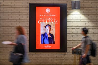 Students pass by a picture of Dr. Melissa Gilliam at Warren Towers.