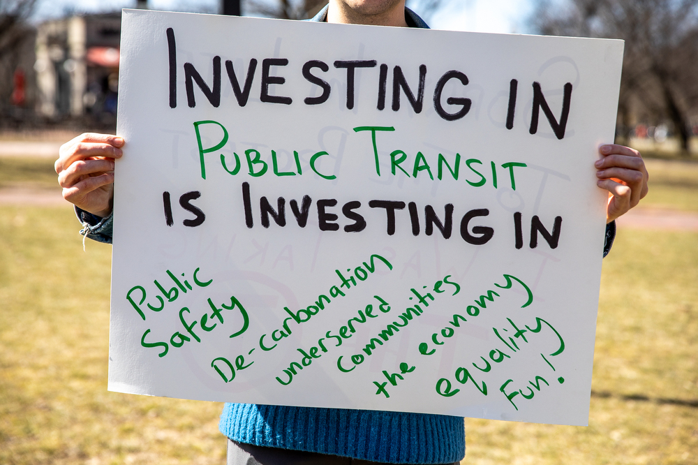 A protester holds a sign promoting investment in public transport