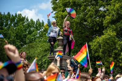Two pride parade attendees stand on a column on June 10, 2023.