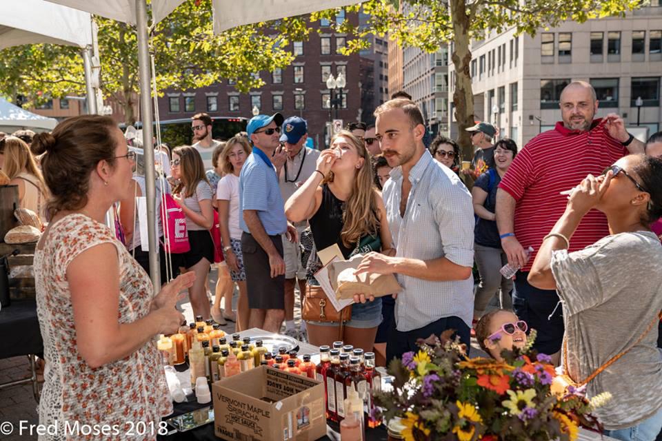 A vendor talks to customers at the 2018 Boston Local Food Festival at the Rose Kennedy Greenway. Hosted by the Sustainable Business Network of Massachusetts, the event returns on Sunday for its 10th anniversary. COURTESY OF FRED MOSES
