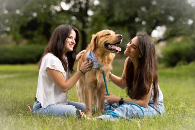 Two girls sitting around a dog