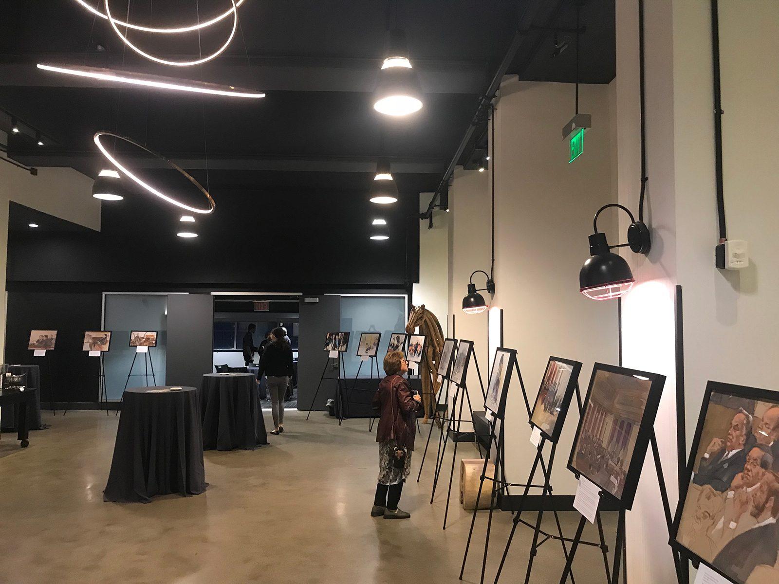 Visitors view courtroom sketches on display at a gallery fundraiser hosted at the Revere Hotel in Downtown Boston that is ongoing through November. LILY KEPNER/ DAILY FREE PRESS STAFF