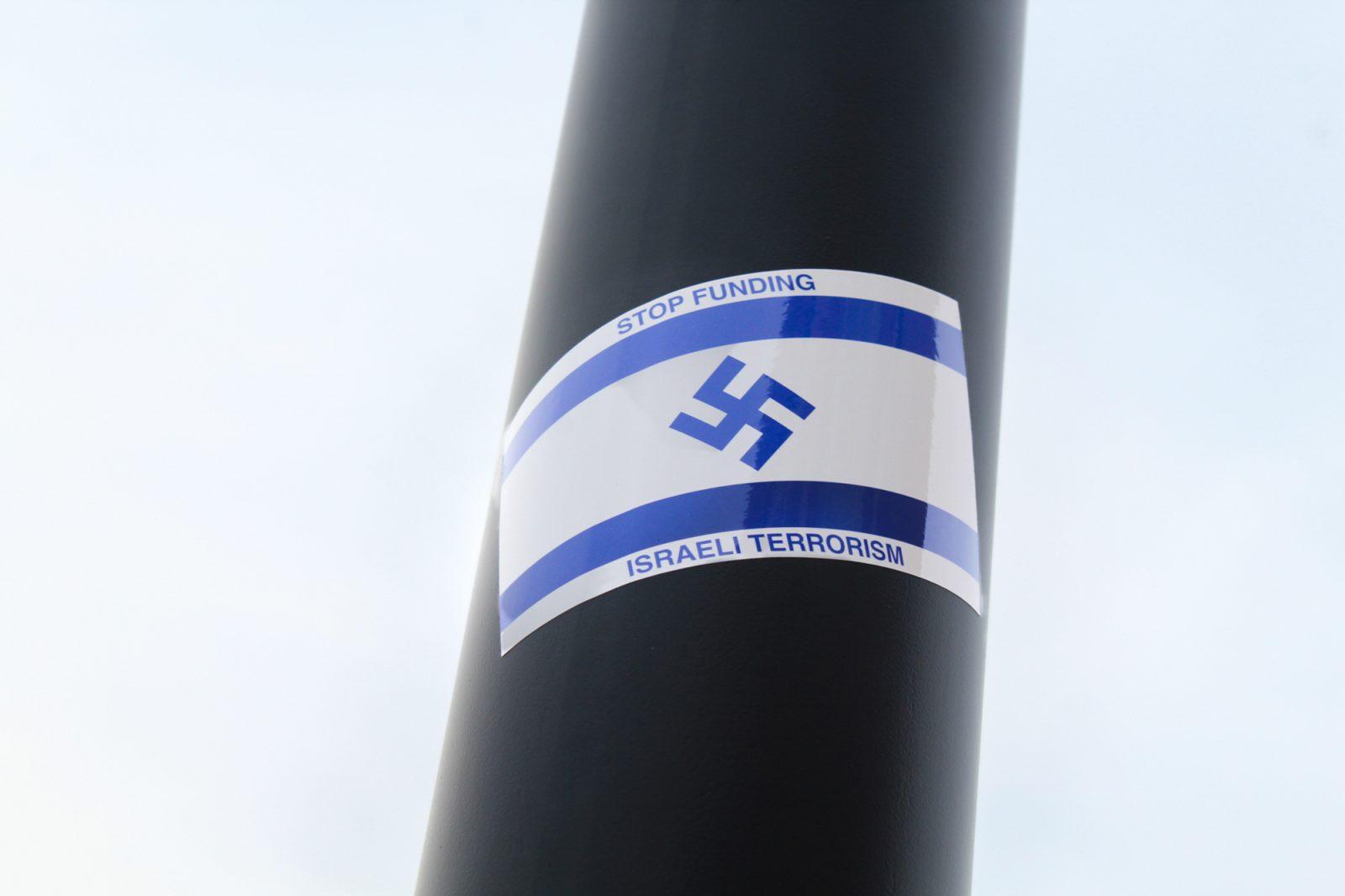 An antisemitic sticker with Nazi signage that says “Stop Funding Israeli Terrorism” stuck on a lamppost at the intersection of Commonwealth Avenue and Harry Agganis Way. Boston University is one of 60 universities under investigation by the United States Department of Education for Title VI violations “relating to antisemitic harassment and discrimination,” according to a March 10 press release from the DOE Office for Civil Rights. SARAH CRUZ/DFP PHOTOGRAPHER 
