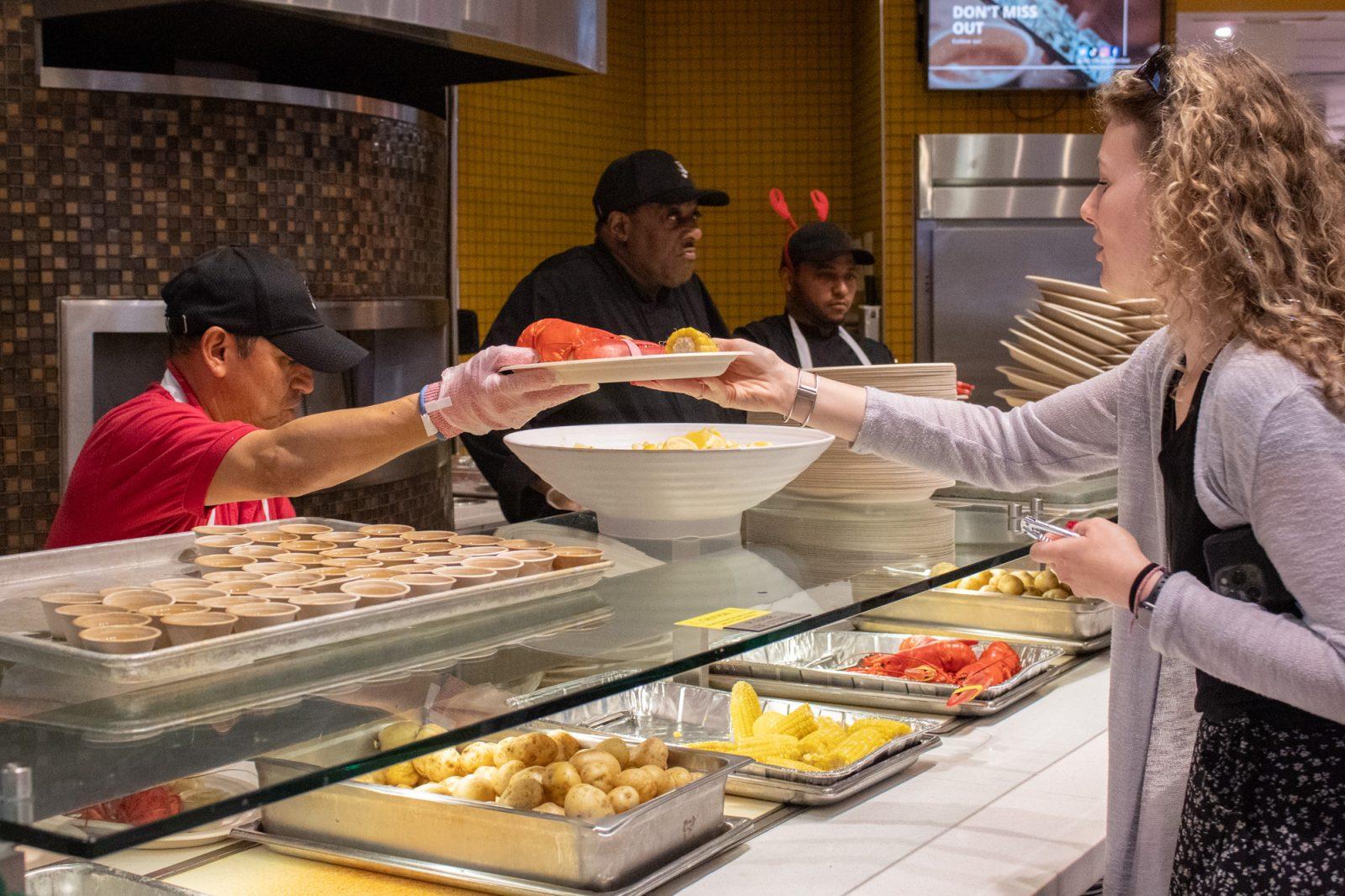 A student grabs a plate of lobster and sides during Lobster Night in Marciano Dining Hall on Sept. 19. Boston University Dining Services is committed to reducing waste coming into Lobster Night, and students met the annual tradition with mixed reactions. SARAH CRUZ/DFP PHOTOGRAPHER