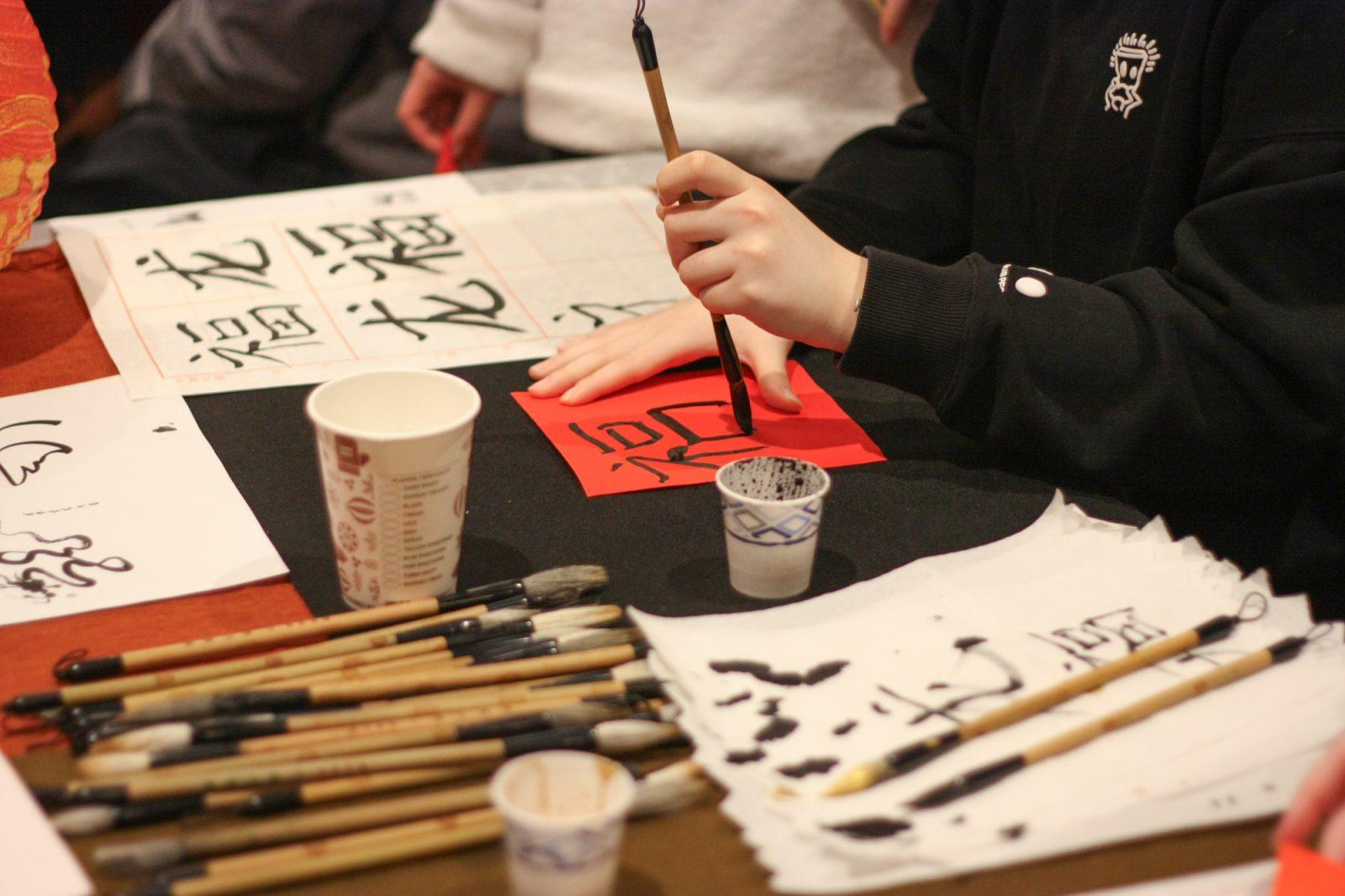 Students practice calligraphy at the Lunar New Year Culture Fair co-hosted by the Chinese Program and Global House at Myles Standish Hall on Friday. CORINNE DAVIDSON/DFP PHOTOGRAPHER