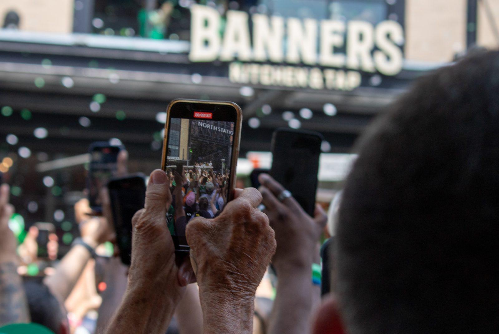 A fan records a video on their phone during the Boston Celtics Championship parade. Lifelong fans of the Celtics arrived at the parade on Friday as early as four hours before the scheduled start time to celebrate their team. HOLLY GUSTAVSEN/DFP PHOTOGRAPHER 