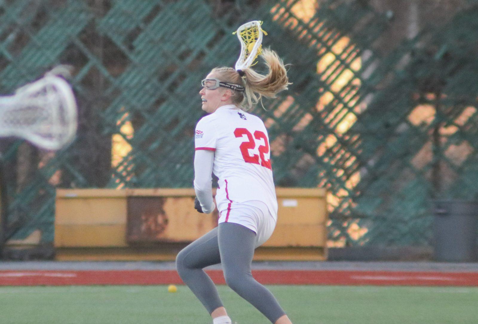 Junior midfielder Avery Jones (22) cradles the ball down the field during a game against University of New Hampshire on Feb. 14. The Terriers fell to Boston College 23-5 on Wednesday. LILY HANSEN/ DFP PHOTOGRAPHER