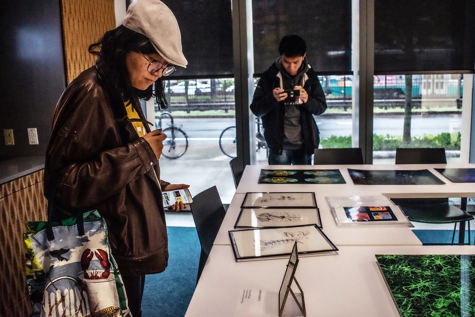 Visitors browse art pieces on display at the NeuroArts Forum hosted at the Rajen Kilachand Center for Integrated Life Sciences &amp; Engineering on Friday. LAURYN ALLEN/ DAILY FREE PRESS STAFF