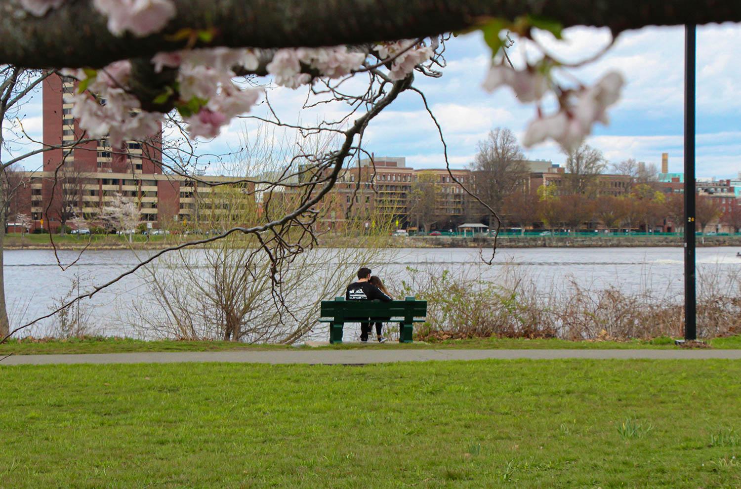 Two people sitting on a bench by the Charles River Esplanade. Maya writes about how the Esplanade became a safe, comfortable place for her to decompress this semester. THALIA LAUZON/ DFP FILE
