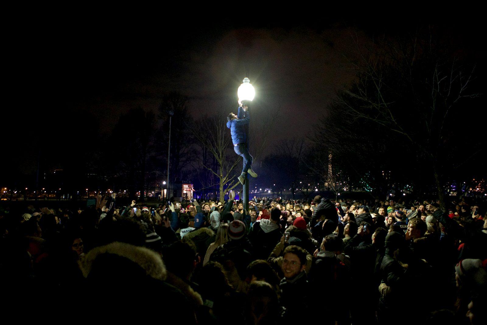 A man climbs a lamp pole in the middle of a crowd of fans who swarmed the Boston Common after the Patriots’ win. OLIVIA FALCIGNO/ DAILY FREE PRESS STAFF