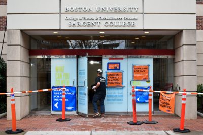 A construction worker entering the front door of Sargent College